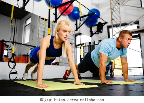 一个妇女的照片在与她的私人教练的健身房里做俯卧撑